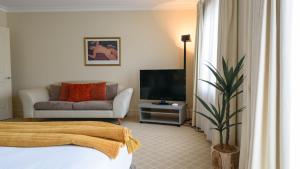 a living room with a bed and a tv and a couch at Lakeside Suite 3 - Lake View & Spa Bath in Daylesford