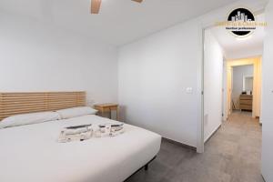 a bedroom with a large white bed and a bathroom at Apartamento Camino Lago in Torremolinos