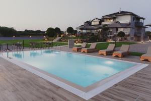 a large swimming pool with chairs and tables and a house at ALS COMFORT SUITES in Preveza