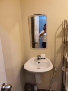 a woman taking a picture of a white sink in a bathroom at MARIDAN AVIDA CONDO in Iloilo City