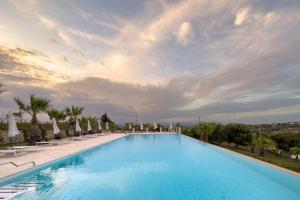 a large swimming pool with chairs and umbrellas at Borgo Vita Novella in Marzamemi
