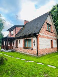 ein altes Backsteinhaus mit einem Rasenhof in der Unterkunft Vīnkalni in Plieņciems