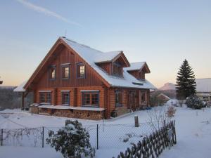 Una gran casa de madera con nieve. en Ferienwohnung im Blockhaus Rosenkranz, en Rathmannsdorf