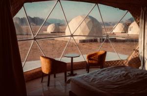a room with a large window with a bed and a table at Fun Camp Wadi Rum in Wadi Rum