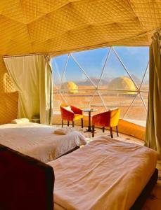 a bedroom with a bed and chairs and a large window at Fun Camp Wadi Rum in Wadi Rum