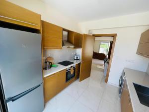 a kitchen with wooden cabinets and a stainless steel refrigerator at City Center Villa 7ms to Mall & Beach in Paphos