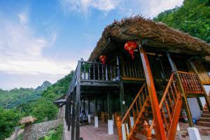 a building with a thatch roof and a balcony at Ba Be Jungle Houses in Ba Be18