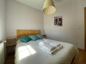 1 dormitorio con 1 cama blanca grande y toallas. en A Casiña, en Monforte de Lemos
