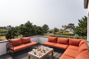 eine Terrasse mit zwei orangenen Sofas und einem Tisch in der Unterkunft Villa de la Roche - Magnifique villa vue mer in Saint-Malo