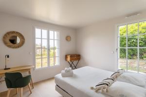 a white bedroom with a bed and a desk and windows at Villa de la Roche - Magnifique villa vue mer in Saint Malo