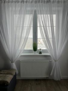 - une chambre avec des rideaux blancs et une fenêtre dans l'établissement Apartmány Vila Vlasta Vysoké Tatry, à Starý Smokovec