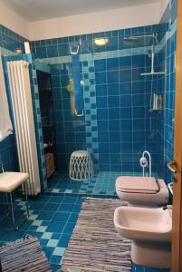 a blue tiled bathroom with a toilet and a shower at Camera nella Casa dei Tigli in Treviso