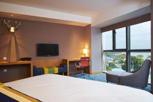 um quarto de hotel com uma cama e uma televisão em Aloft Dongguan Songshan Lake em Dongguan