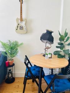 una mesa con 2 sillas y una guitarra en una habitación en Grade II boho home in the heart of Oxford St. en Southampton