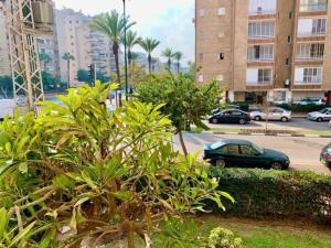 a green car parked in a parking lot with buildings at Family House in Natanya in Netanya