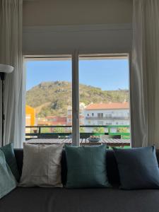 a couch with pillows in front of a large window at Calma Marína Roses in Roses