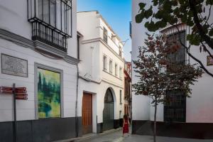 une femme marchant dans une rue à côté des bâtiments dans l'établissement Magno Apartments Fabiola 7 Luxury House, à Séville