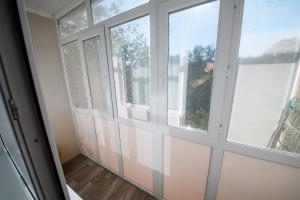 um quarto com duas janelas e uma pessoa a olhar para fora em Металлургов 10 em Temirtaū