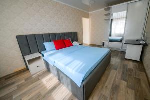um quarto com uma cama grande e almofadas vermelhas em Металлургов 10 em Temirtaū