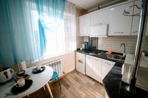 a small kitchen with a table and a sink at Металлургов 10 in Temirtaū