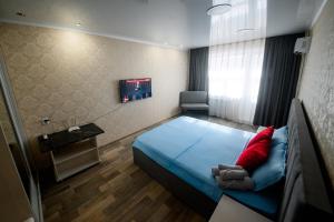 um quarto com uma cama azul e uma almofada vermelha em Металлургов 10 em Temirtaū
