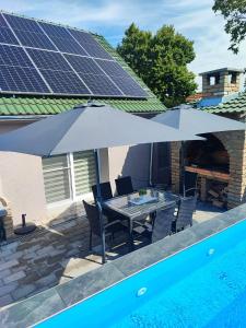 a table and chairs under an umbrella next to a pool at Villa Klaudija in Petrovaradin