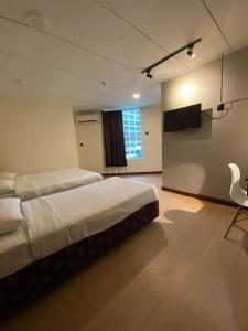 a bedroom with two beds and a flat screen tv at CU Boutique Hotel in Kota Kinabalu