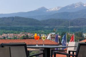 dois copos de vinho sentados numa mesa na varanda em Ruskovets Thermal SPA & Ski Resort em Bansko
