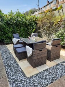 een patio met een tafel en rieten stoelen bij Coddiwomple in Leyburn