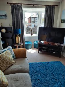 ein Wohnzimmer mit einem Sofa und einem Flachbild-TV in der Unterkunft Coddiwomple in Leyburn