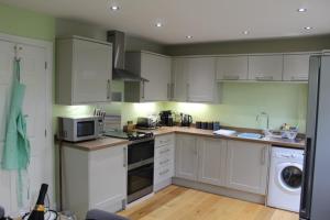 a kitchen with white cabinets and a microwave at Coddiwomple in Leyburn
