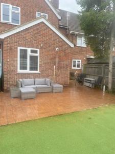a patio with a couch in front of a brick house at Lovely 2 bed apartment sleeps 5 in Abingdon
