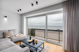 een woonkamer met een bank en een groot raam bij Dune Rose - flat with frontal sea view in Middelkerke