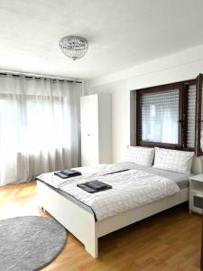 a white bedroom with a large bed and a window at Stilvolles Apartment nahe Therme und PreZero Arena in Sinsheim