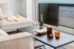 una sala de estar con una botella de vino y copas en una mesa en Dune Rose - flat with frontal sea view, en Middelkerke