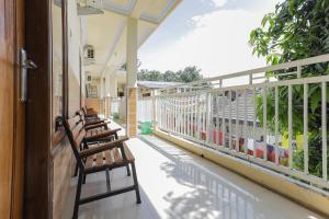 a porch with wooden chairs sitting on a balcony at RedDoorz Syariah near Alun Alun Pasuruan in Pasuruan