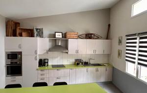 uma cozinha com armários brancos e um balcão verde em Séjour au vert em Vert