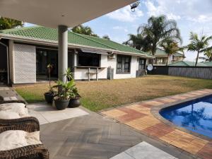 a backyard with a swimming pool and a house at Umhlanga Rocks Guesthouse flat in Durban