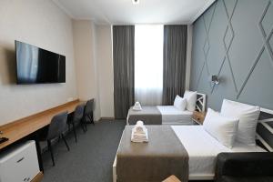 a hotel room with two beds and a flat screen tv at Prime Hotel in Gyumri