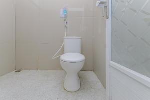 a white bathroom with a toilet and a shower at RedDoorz Syariah near Alun Alun Pasuruan in Pasuruan