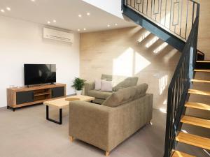 sala de estar con sofá, TV y escaleras en Casa Rural Reserva de las Nieves en Tolox