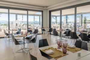 uma sala de jantar com mesas, cadeiras e janelas em Hotel Condesa em Port d'Alcudia