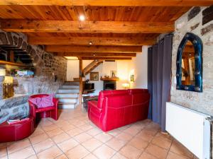 een woonkamer met rode meubels en een stenen muur bij Holiday Home Le Rouge Borne - LVS110 by Interhome in Sainte-Marguerite-Lafigère