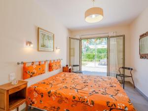a bedroom with a bed with an orange bedspread at Holiday Home Arbelle by Interhome in Saint-Cézaire-sur-Siagne