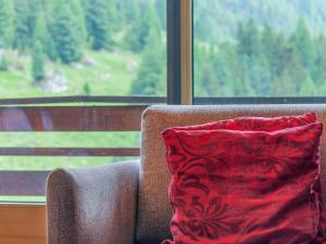 a red pillow sitting on a couch in front of a window at Apartment Rosablanche C61 by Interhome in Siviez