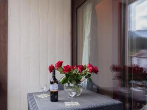 a table with a vase of roses and a bottle of wine at Apartment Rosablanche C51 by Interhome in Siviez