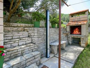 an outdoor oven with a stone wall and a fireplace at Apartment Haus Peric - KOR200 by Interhome in Prigradica