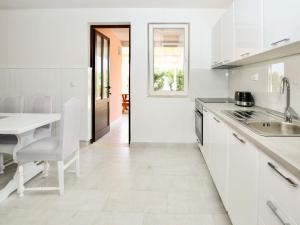a kitchen with white cabinets and a white table at Apartment Haus Peric - KOR200 by Interhome in Prigradica