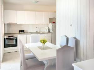a kitchen with white cabinets and a white table and chairs at Apartment Haus Peric - KOR200 by Interhome in Prigradica