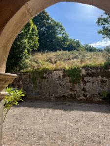 une arche au-dessus d'un mur en pierre avec des arbres et des buissons dans l'établissement Domaine du Très-Haut - Château de Montanges, à Montanges